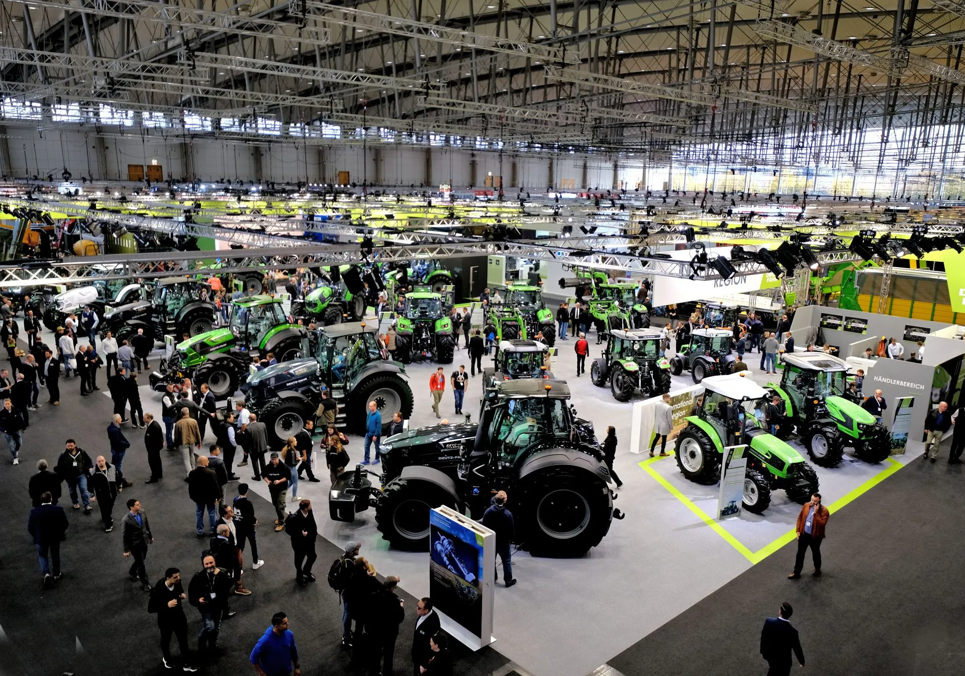 Deutz-Fahr tractors on display at an agricultural trade show, with attendees walking through the exhibition hall.